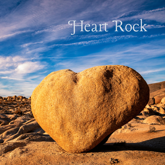 Heart-shaped rock formation magnet in Joshua Tree National Park with blue desert sky and warm California desert landscape.