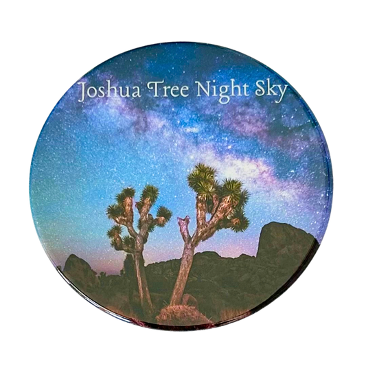 Square coaster featuring a photo of two Joshua trees silhouetted against a vivid Milky Way night sky with violet and blue hues over Joshua Tree National Park.