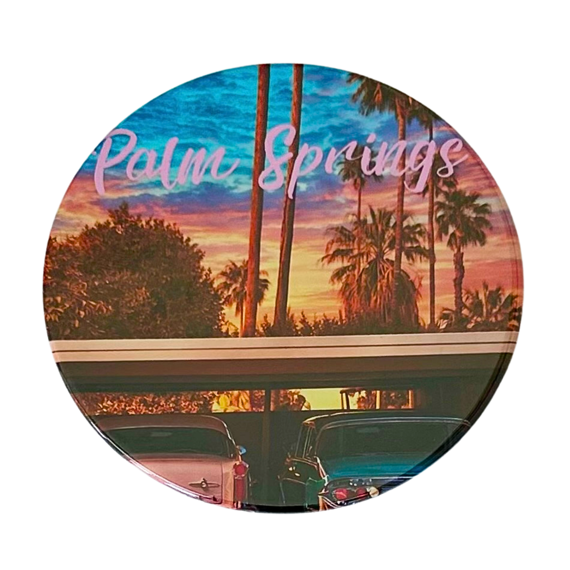 Round 3.5" Palm Springs coaster featuring two classic vintage cars, one pink and one teal, parked at sunset with silhouetted palms and a dreamy pink and orange sky.