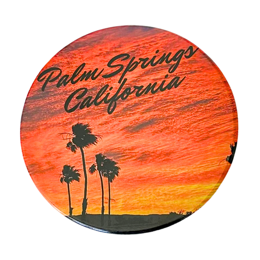 Round 3.5" Palm Springs California coaster featuring silhouetted palm trees against a dramatic orange and red sunset sky with bold script lettering.