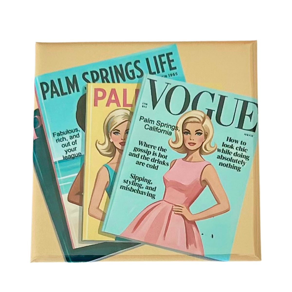 A stack of retro-style magazine covers on a magnet. The most prominent cover is Vogue Palm Springs California featuring a blonde woman in a pink dress on a turquoise background, with Palm Springs Life and other vintage covers partially visible behind it.